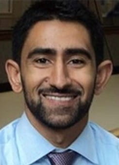 Image from shoulders up of Dr. Shah wearing a blue shirt and colorful tie.