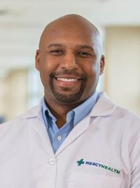 Headshot of a man in a light blue shirt wearing a Mercy Health doctor's coat.