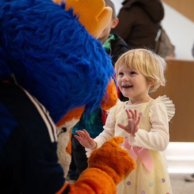 Young girl, about four years old, interacting with the FC Cincinnati lion mascot.